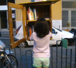 Una bambina mette dei libri nella libretta di piazza Garibaldi 